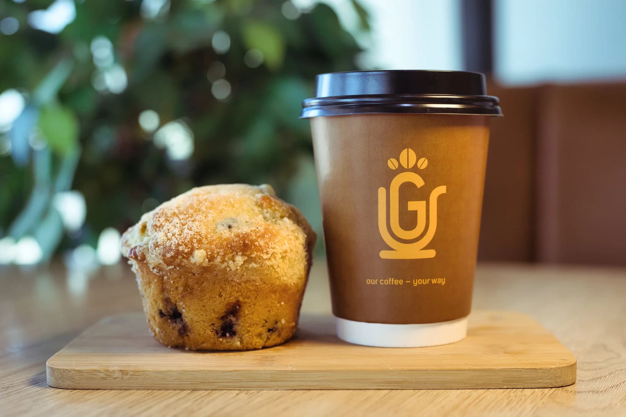 A Grande Cafe branded takeaway cup with a fresh muffin